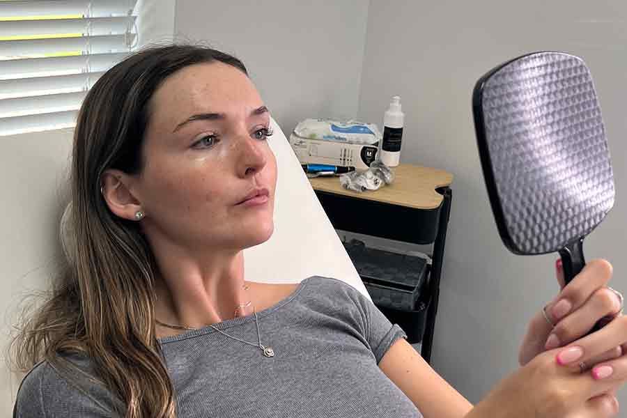 woman in  beutician chair looking at herself in a mirror