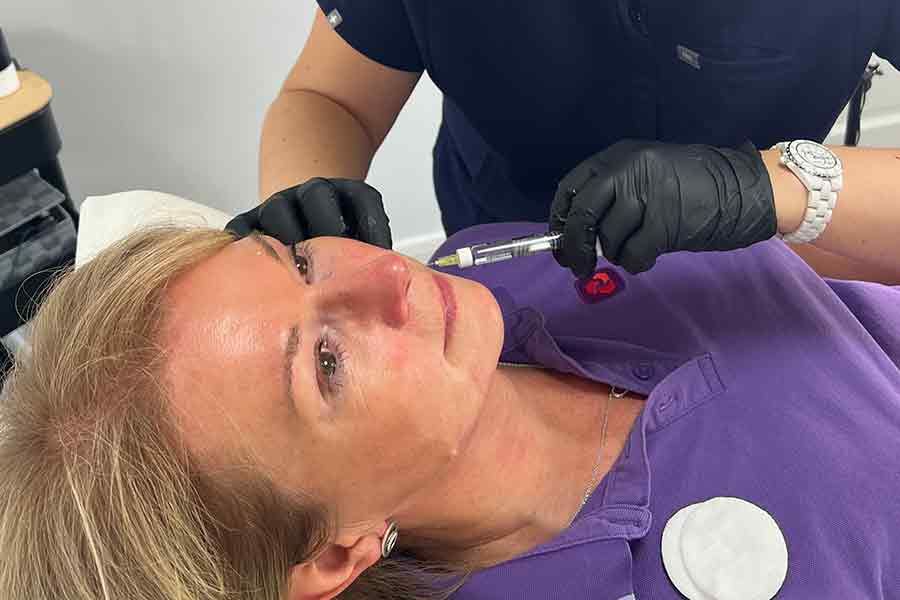 woman receiving a skin booster injection in her chin